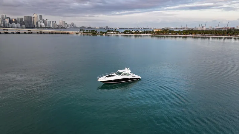 Slide: The Image of 2008 Sea Ray 48 Sundancer yacht on calm waters with city skyline in the background. - 19