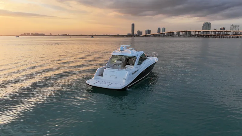 Slide: The Image of 2008 Sea Ray 48 Sundancer yacht on calm water at sunset, city skyline in background. - 9