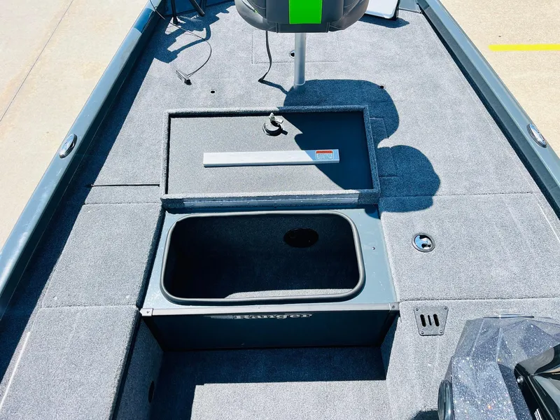 Slide: The Image of 2025 Ranger RT188C boat interior with open storage compartment, gray carpet, and seating area. - 23