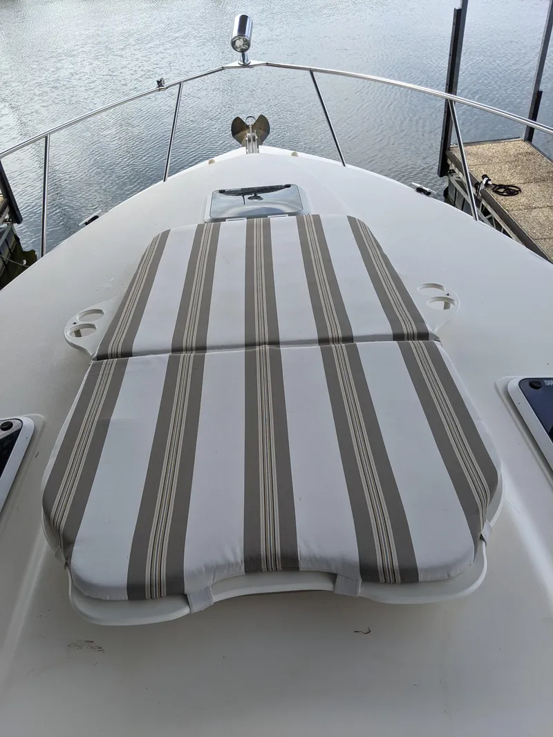 Slide: The Image of 2004 Rinker Fiesta Vee 410 boat with striped deck cushions, docked by the water. - 11