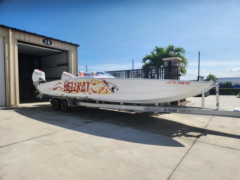 Slide: The Image of 2022 HellCat 32 Wide Body boat on trailer outside a garage. - 2