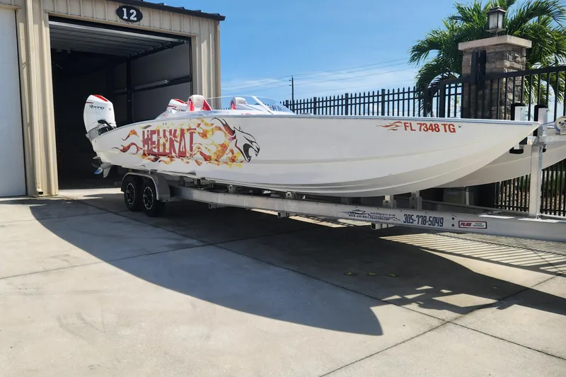 Slide: The Image of 2022 HellCat 32 Wide Body boat on trailer, parked outside a garage. - 3