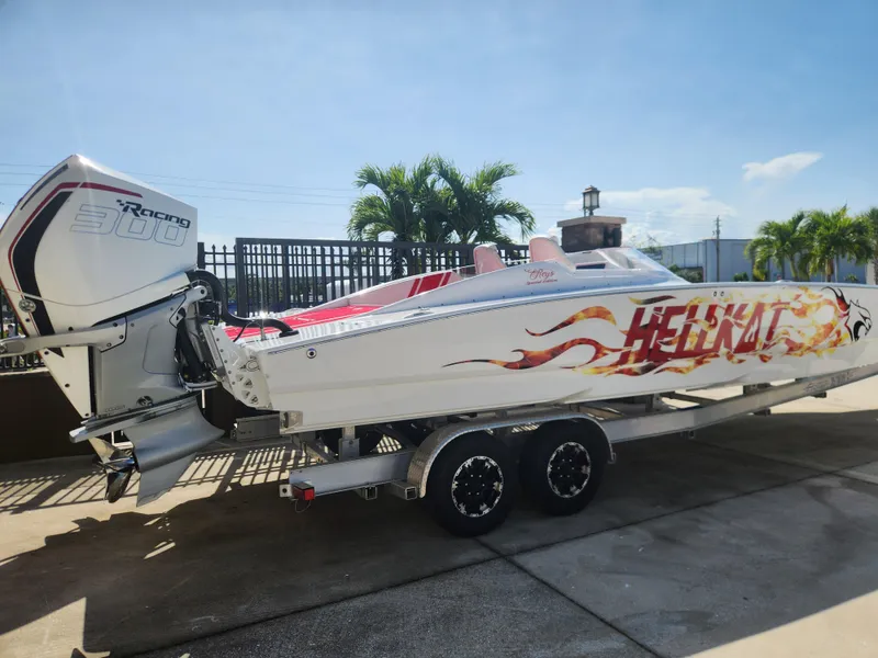Slide: The Image of 2022 HellCat 32 Wide Body boat with vibrant graphics on a trailer, parked outdoors. - 9