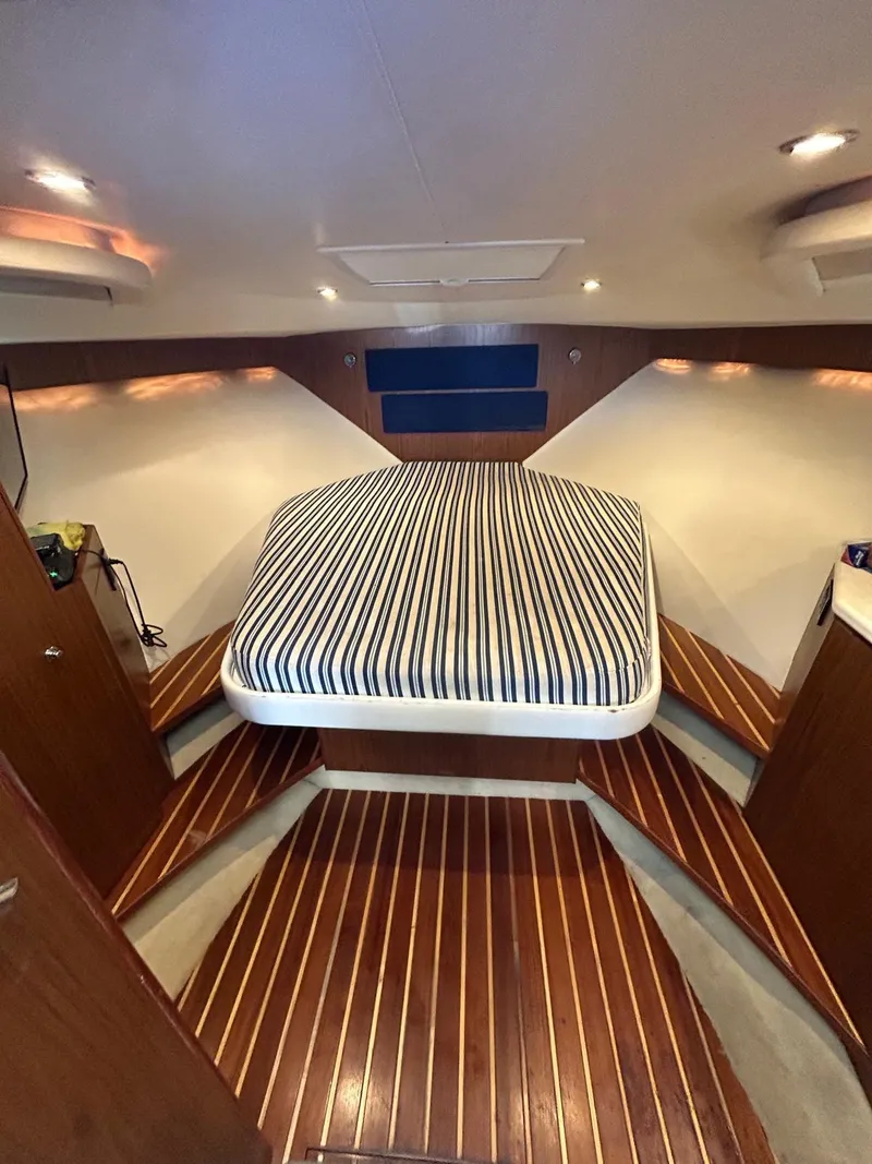 Slide: The Image of 2015 Tiara Yachts 3100 Coronet cabin with striped bedding and wooden flooring. - 11