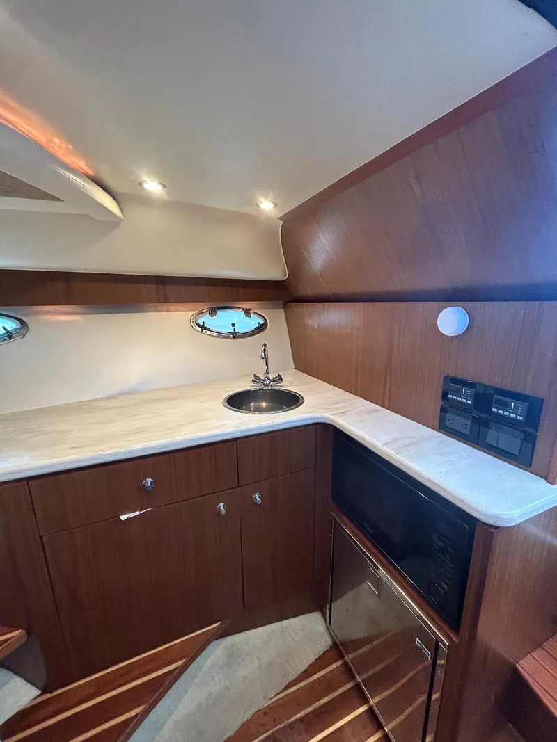 Slide: The Image of 2015 Tiara Yachts 3100 Coronet interior with wood cabinetry and compact kitchenette. - 12