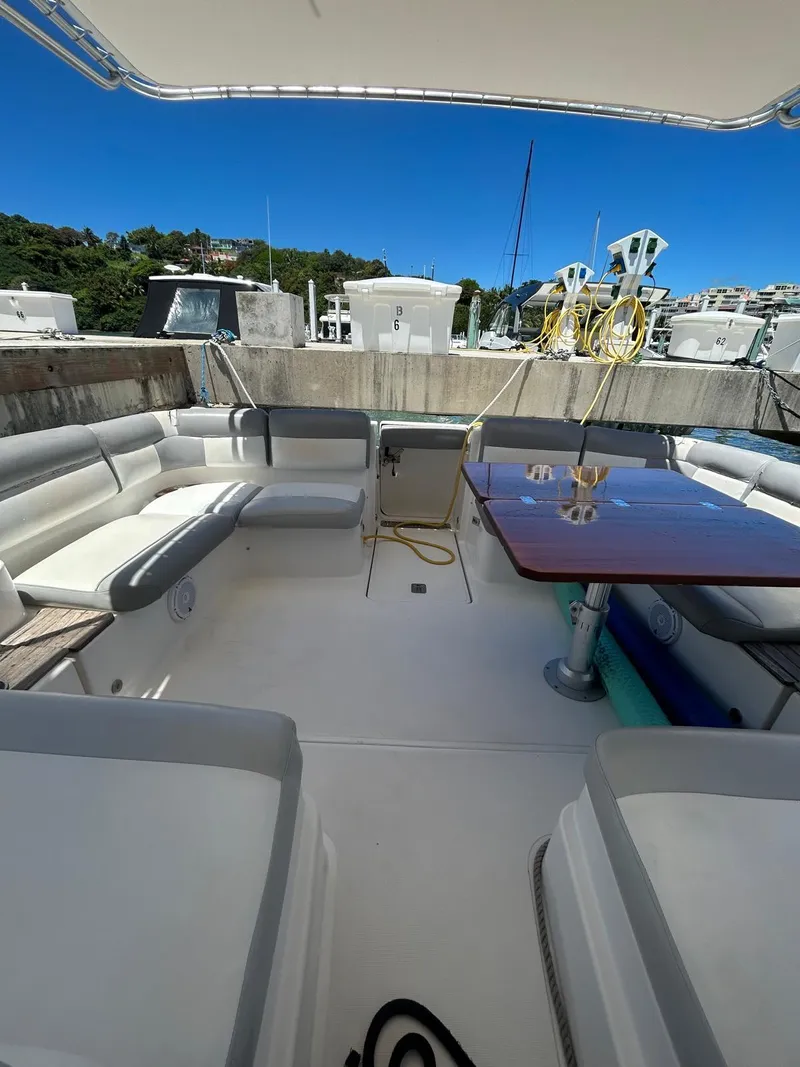 Slide: The Image of 2015 Tiara Yachts 3100 Coronet with spacious seating and table, docked under clear blue sky. - 6