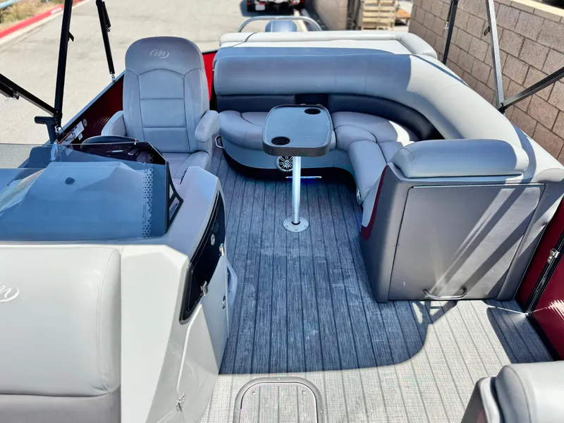 Slide: The Image of 2019 Manitou 23 Oasis boat interior with gray seating and a small table. - 12