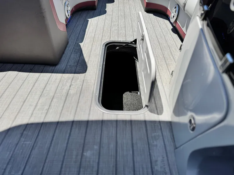 Slide: The Image of 2019 Manitou 23 Oasis boat interior with open storage compartment on deck. - 13