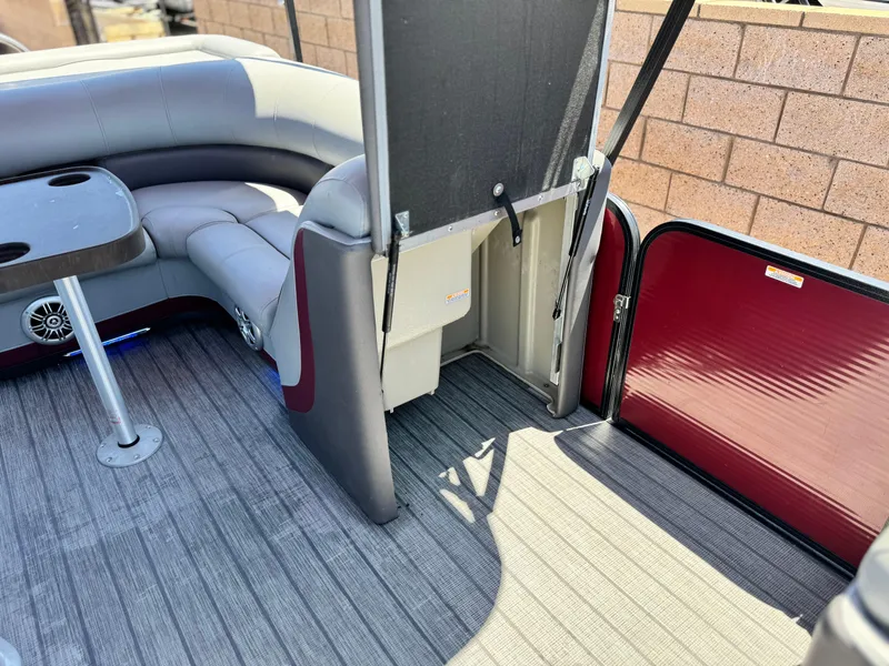 Slide: The Image of 2019 Manitou 23 Oasis boat interior with seating, table, and storage compartment. - 15
