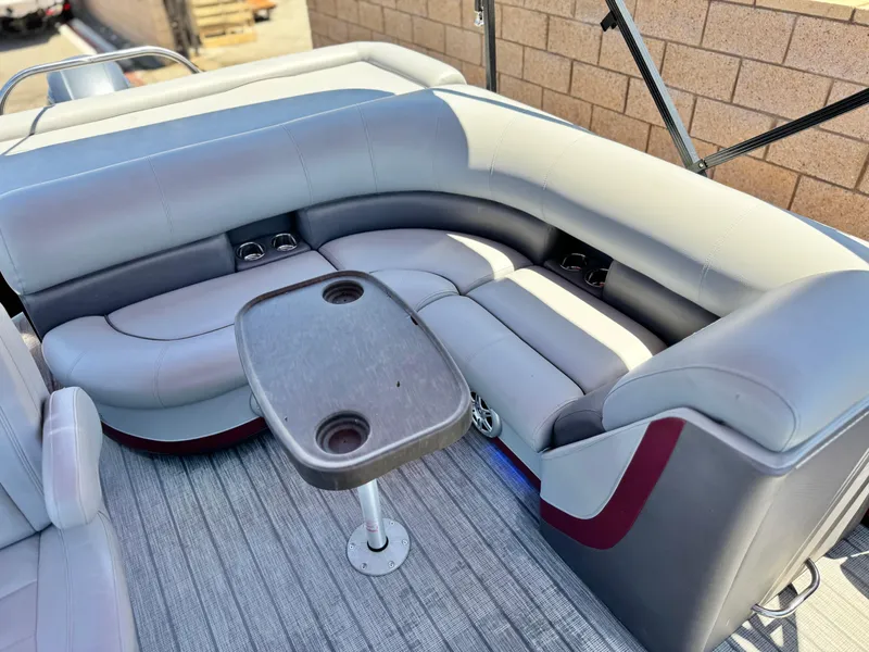 Slide: The Image of 2019 Manitou 23 Oasis boat interior with gray seating and a small table. - 16