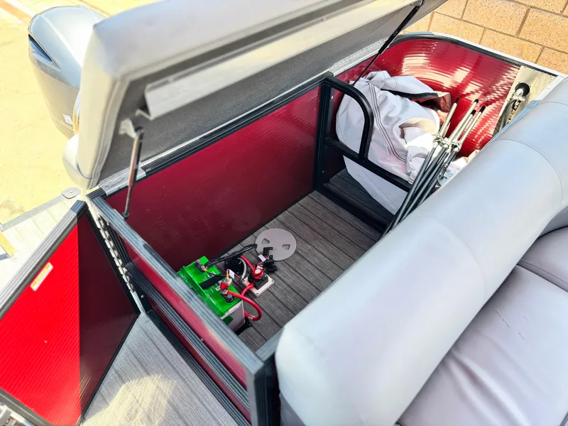 Slide: The Image of Open storage compartment in 2019 Manitou 23 Oasis boat, showing battery and equipment. - 19