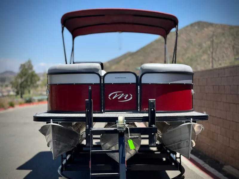 Slide: The Image of 2019 Manitou 23 Oasis pontoon boat on trailer, red and gray design, mountain background. - 2