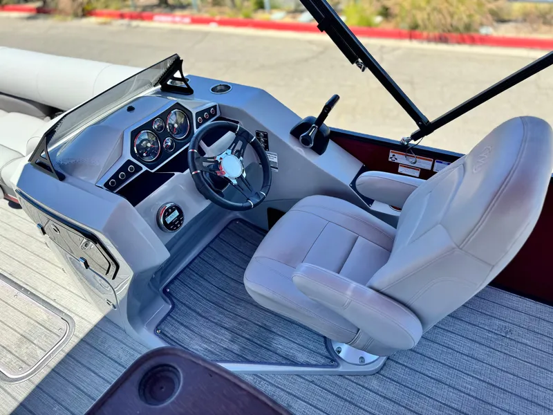 Slide: The Image of 2019 Manitou 23 Oasis boat cockpit with steering wheel and captain's chair. - 22