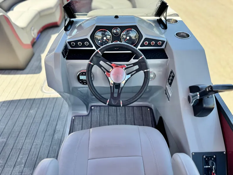 Slide: The Image of 2019 Manitou 23 Oasis boat dashboard with steering wheel and control panel. - 23