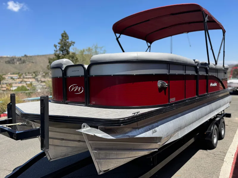 Slide: The Image of 2019 Manitou 23 Oasis pontoon boat with red exterior and canopy on a trailer. - 4