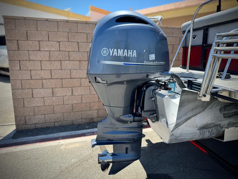 Slide: The Image of Yamaha outboard motor on 2019 Manitou 23 Oasis boat, parked near a brick wall. - 7