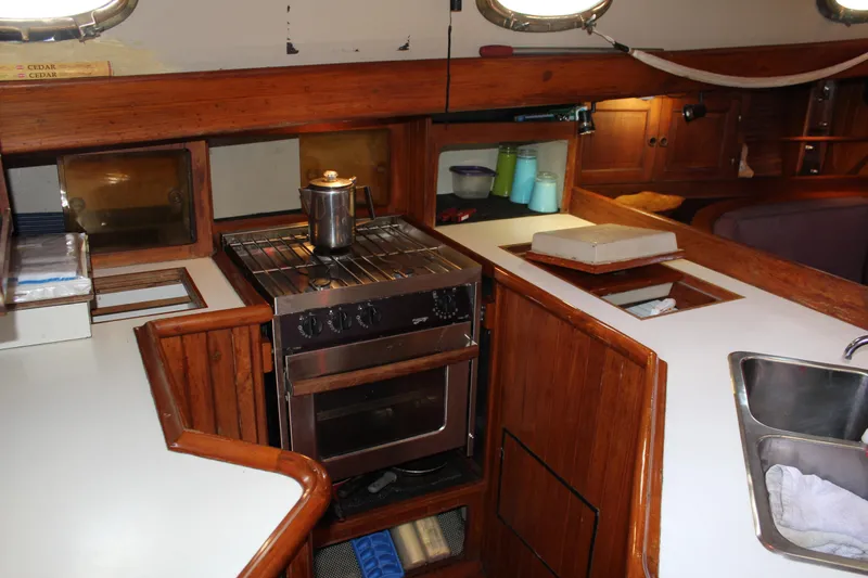 Slide: The Image of 1979 Hans Christian 38 Ketch galley with stove, sink, and wooden cabinetry. - 16