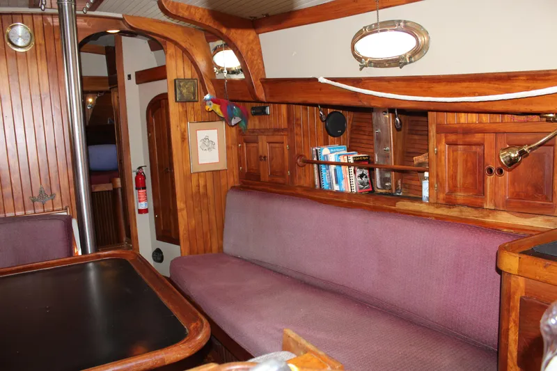 Slide: The Image of Interior of a 1979 Hans Christian 38 Ketch with wooden paneling and purple seating. - 9