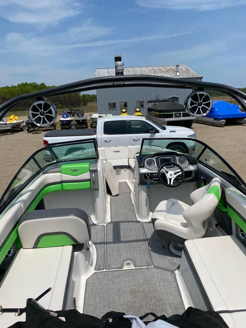 Slide: The Image of 2016 Chaparral Vortex 223 VRX boat interior with green accents, parked near vehicles. - 10