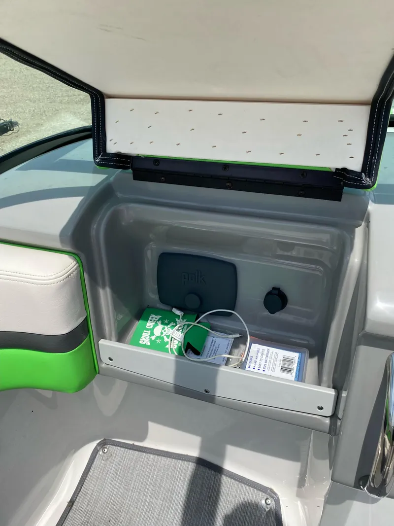 Slide: The Image of 2016 Chaparral Vortex 223 VRX boat storage compartment with green accents and Polk audio system. - 8