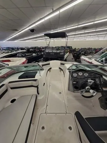 Slide: The Image of 2015 Yamaha Boats AR210 interior view in a showroom with other boats. - 11