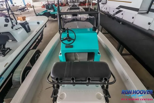 Slide: The Image of 2025 Majek 18 M2 boat with teal console, black seat, and steering wheel in showroom. - 8