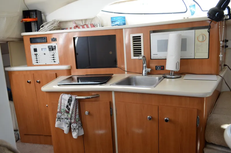 Slide: The Image of 2001 Bayliner 2655 Ciera boat interior kitchen with sink, stove, and wooden cabinets. - 30