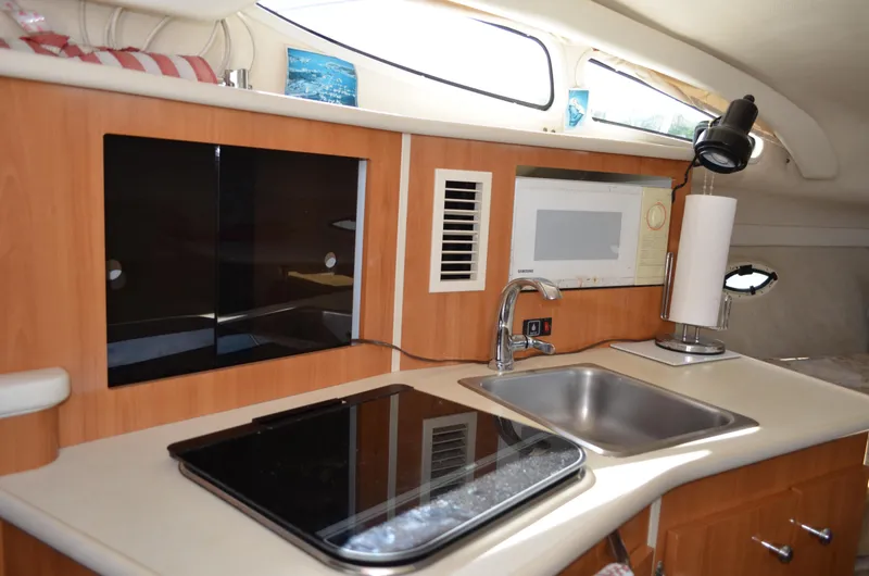 Slide: The Image of 2001 Bayliner 2655 Ciera boat kitchen with sink, stove, and microwave. - 32