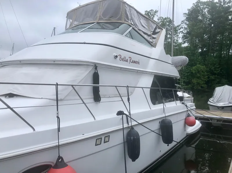 Slide: The Image of 2000 Carver 450 Voyager Pilothouse yacht docked, featuring sleek design and protective fenders. - 12