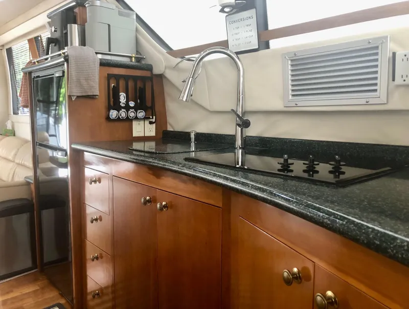 Slide: The Image of 2000 Carver 450 Voyager Pilothouse kitchen with wooden cabinets and modern appliances. - 48