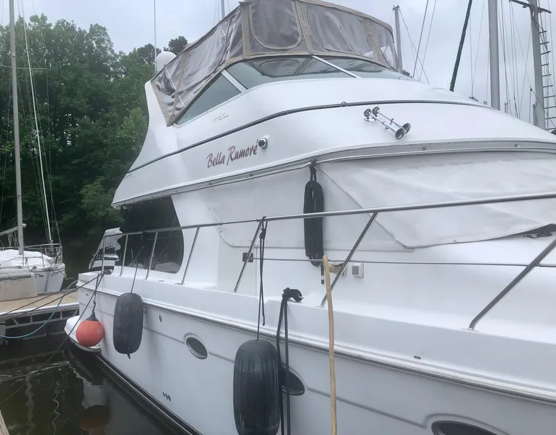 Slide: The Image of 2000 Carver 450 Voyager Pilothouse yacht docked, featuring sleek design and upper deck enclosure. - 6