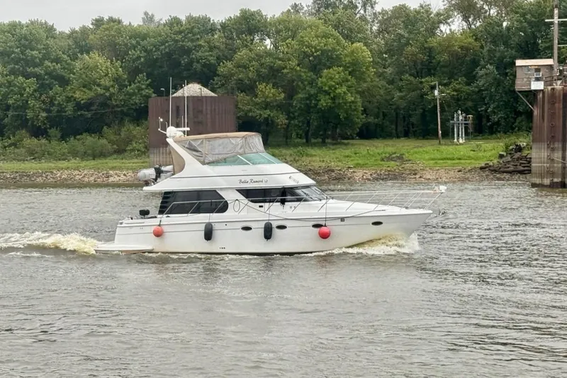 Slide: The Image of 2000 Carver 450 Voyager Pilothouse cruising on a river with lush green trees. - 3