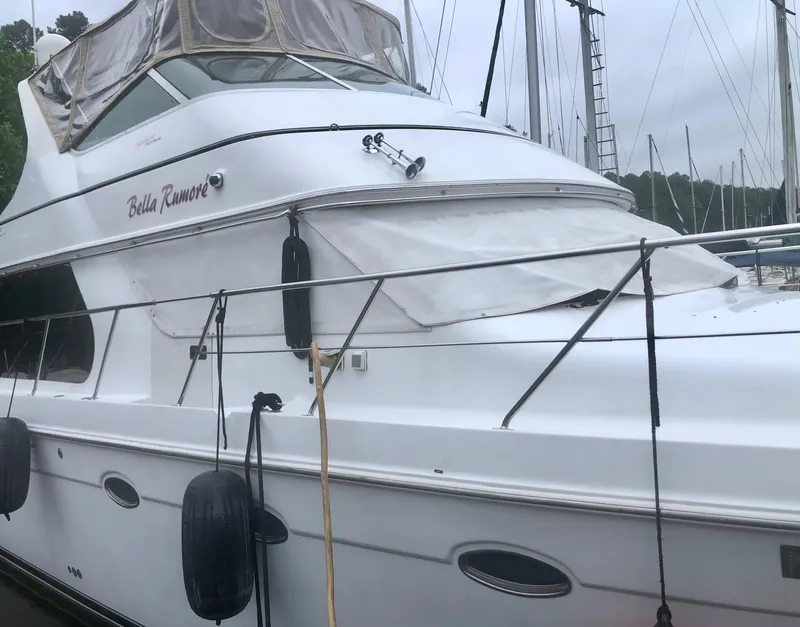 Slide: The Image of 2000 Carver 450 Voyager Pilothouse yacht docked, featuring sleek design and protective covers. - 5