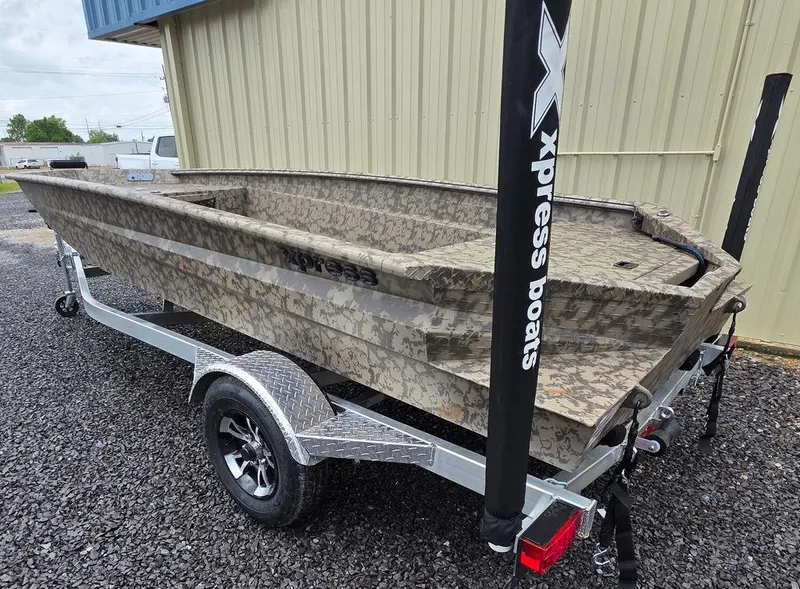 Slide: The Image of 2025 Xpress H18DB boat on trailer, camouflage design, parked on gravel. - 13