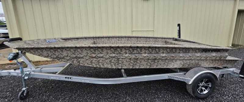 Slide: The Image of 2025 Xpress H18DB boat on trailer, camouflage design, parked on gravel. - 16