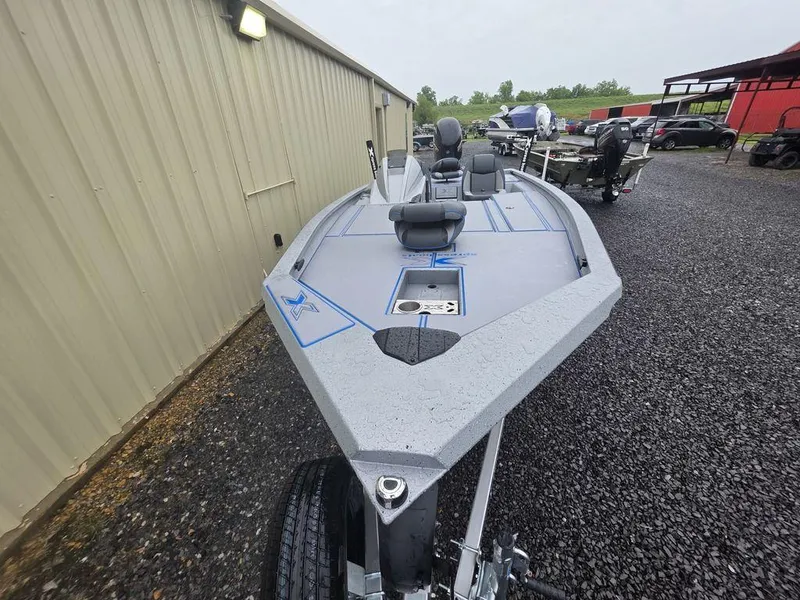 Slide: The Image of 2025 Xpress H20 Bass boat, gray exterior, parked on gravel near a building. - 12