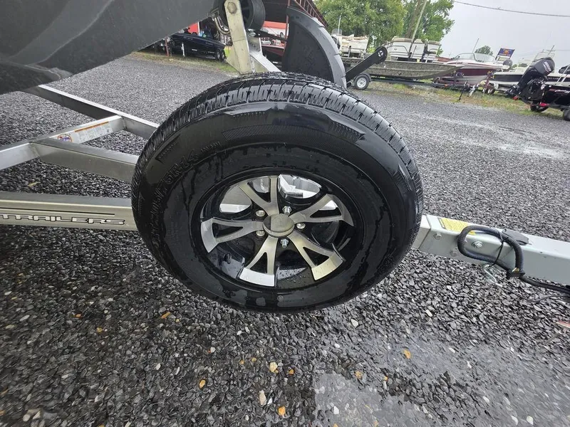 Slide: The Image of Trailer wheel of 2025 Xpress H20 Bass boat on gravel surface. - 13