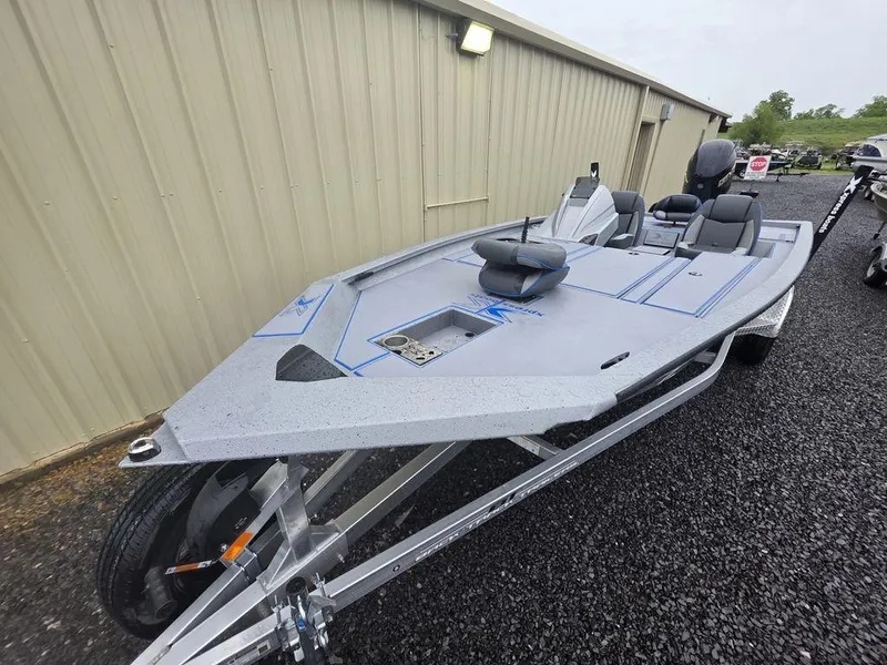 Slide: The Image of 2025 Xpress H20 Bass boat on trailer, parked beside a building. - 15