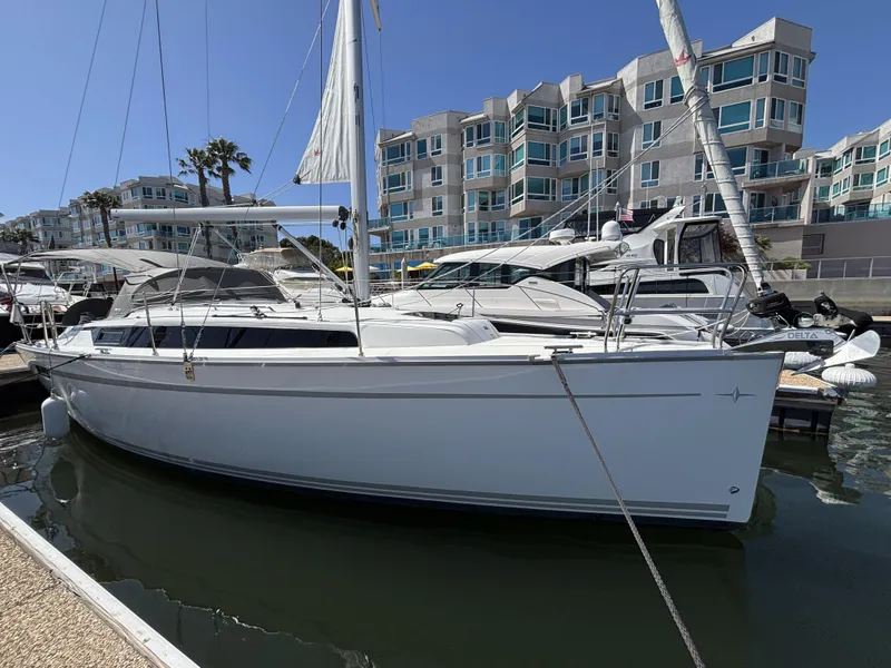 Slide: The Image of 2020 Bavaria Cruiser 34 sailboat docked in marina, modern buildings in background. - 2