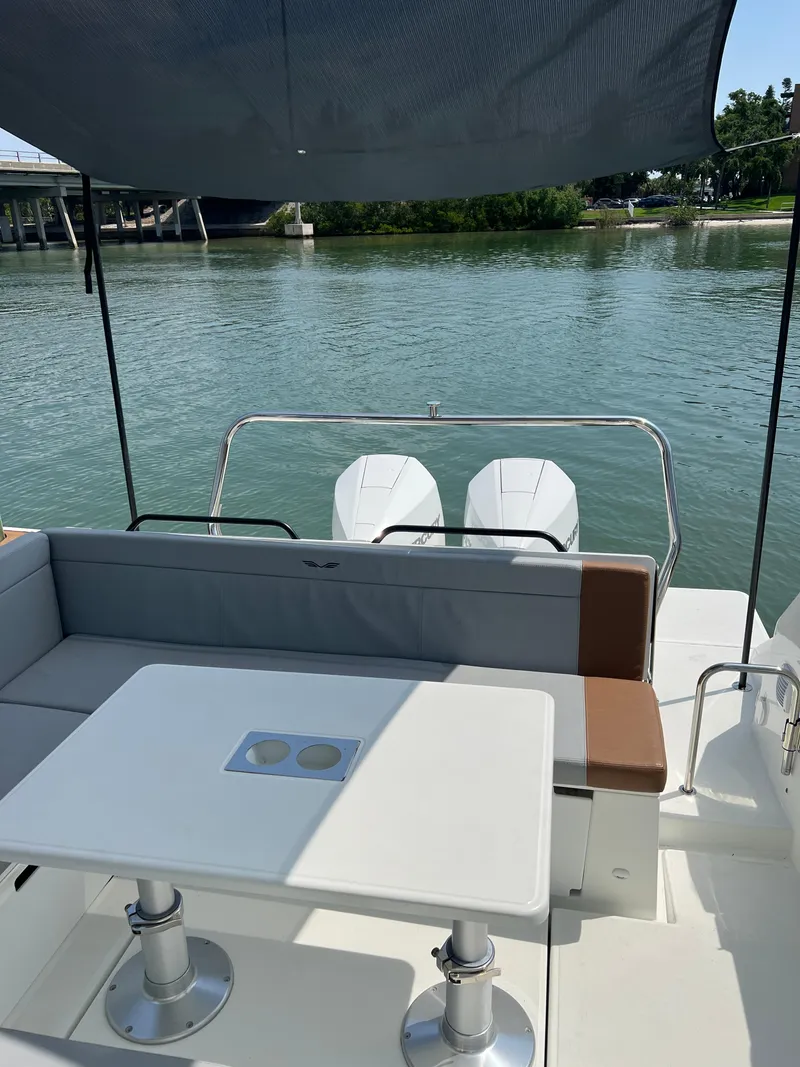 Slide: The Image of 2024 Beneteau 29' Flyer 9 SUNdeck, rear seating area with table, overlooking calm waters. - 17