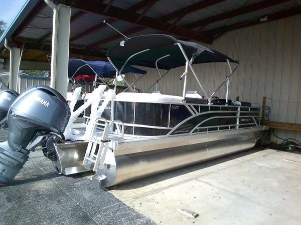 Slide: The Image of 2025 Bennington 22SSR pontoon boat with Yamaha engines, docked under a shelter. - 14