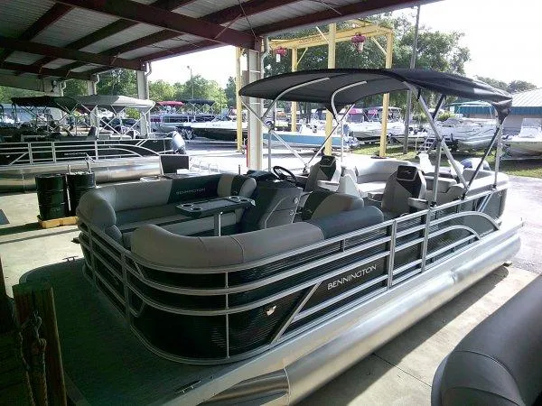 Slide: The Image of 2025 Bennington 22SSR pontoon boat under a covered dock, showcasing sleek design and spacious seating. - 9
