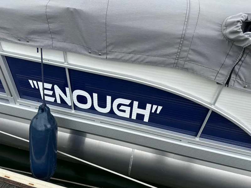 Slide: The Image of 2022 Bennington 24 SSR Quad Bench boat with "ENOUGH" name, covered and docked. - 7