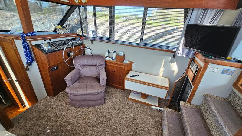Slide: The Image of 1990 Carver 32 Aft Cabin interior with helm, recliner, and TV. - 15