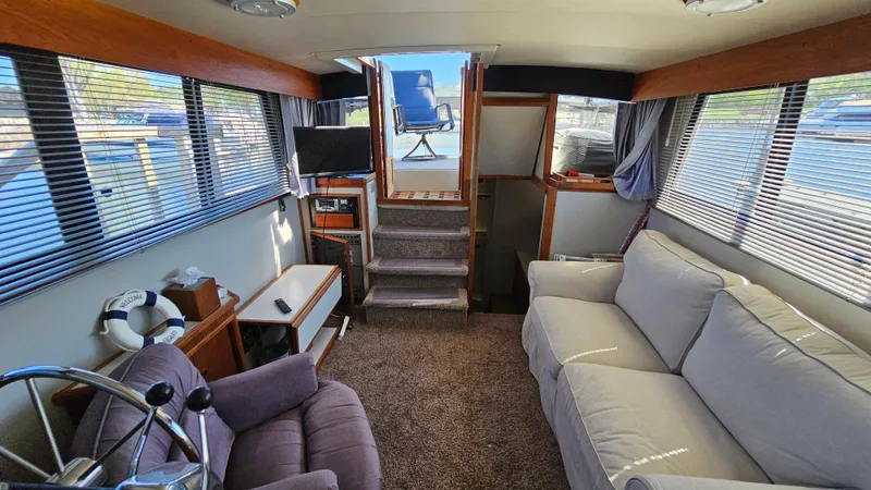 Slide: The Image of 1990 Carver 32 Aft Cabin interior with cozy seating, helm, and large windows. - 16