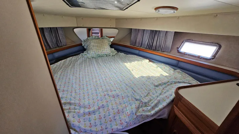 Slide: The Image of 1990 Carver 32 Aft Cabin bedroom with anchor-patterned bedding and natural light. - 21