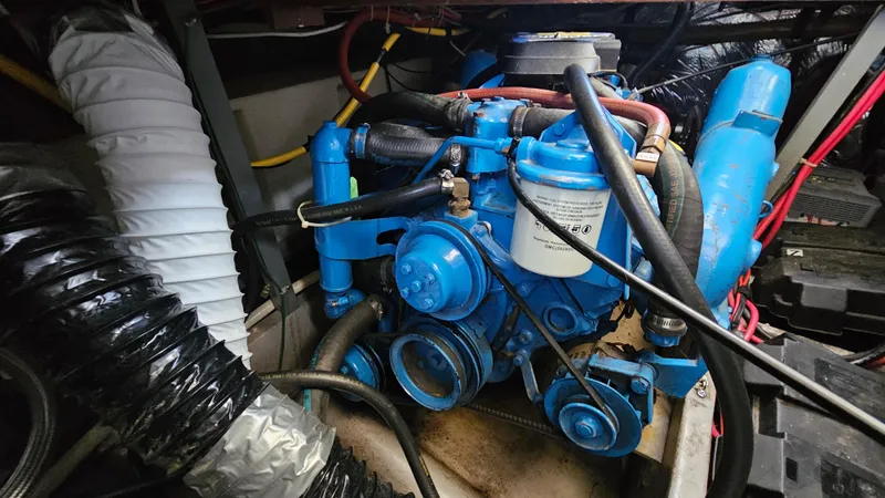 Slide: The Image of Engine compartment of a 1990 Carver 32 Aft Cabin boat, featuring blue machinery and hoses. - 28