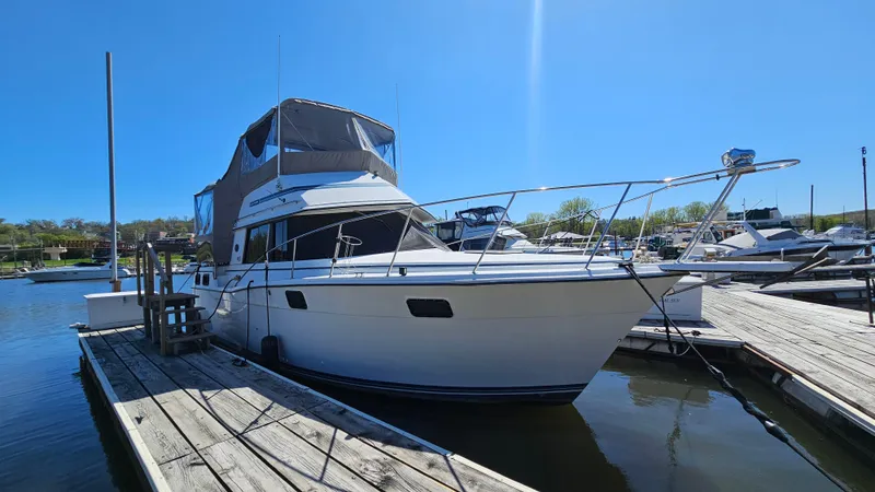 Slide: The Image of 1990 Carver 32 Aft Cabin boat docked at a marina under clear blue sky. - 3