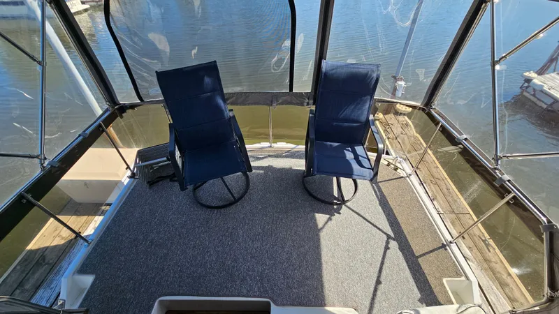 Slide: The Image of 1990 Carver 32 Aft Cabin deck with two blue chairs overlooking water. - 5