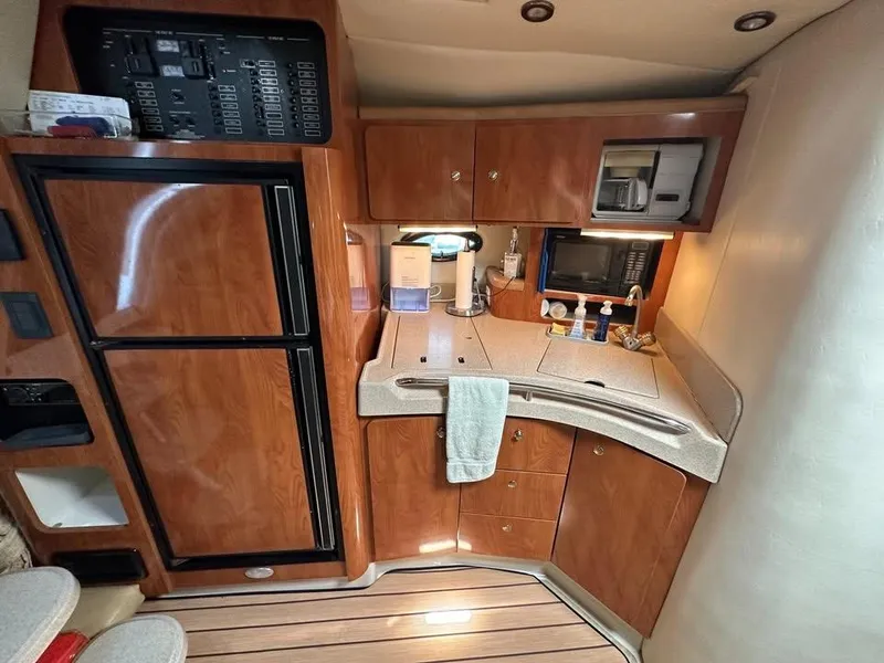 Slide: The Image of 2003 Wellcraft 3700 Martinique yacht kitchen with wood cabinetry, fridge, and microwave. - 6